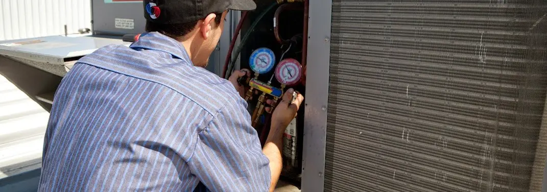 HVAC technician servicing a condenser unit in Nixa
